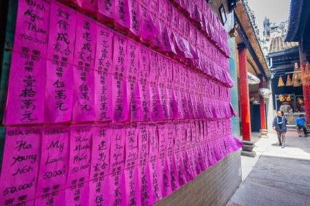 Téléchargez les photos : HO CHI MINH CITY, Vietnam - 8 novembre 2022 - Pagode Chua Ba Thien Hau à Saigon. Dans le temple de Thien Hau. Les gens qui ont fait un don au temple sont immortalisés avec ces notes roses sur le mur - en image libre de droit