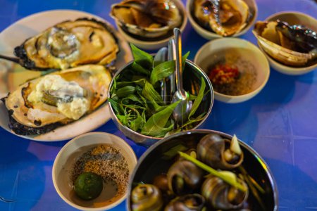 Téléchargez les photos : Plats de rue dans les rues de Saigon. Moules, escargots et huîtres préparés à la vietnamienne. Cuisine vietnamienne la nuit sur le trottoir - en image libre de droit