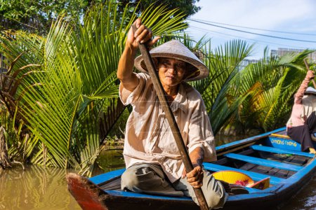 Photo for Ho Chi Minh City, Vietnam- November 9, 2022: Tourism rowing boat in the Mekong delta. Tours on Paddle boats, tourist attraction on the Mekong River. Man with conical Vietnamese hat controls the canoe - Royalty Free Image
