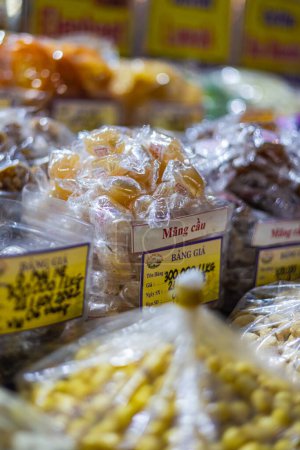 Téléchargez les photos : Ho Chi Minh Ville, Vietnam - 10 novembre 2022 : Noix, Bonbons et fruits secs dans un marché à Saigon. Custard Apple Mang Cau et diverses graines et noix dans une étagère Ben Thanh Market dans le district de Saigon 1 - en image libre de droit