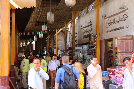 Foto de Dubái, Emiratos Árabes Unidos - 14 de febrero de 2022: El mercado Old Souk de Dubái está lleno de turistas. El mercado es un laberinto de callejuelas estrechas y llenas de gente llena de puestos de venta de productos como especias, textiles, joyas - Imagen libre de derechos
