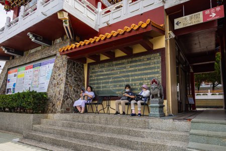 Photo for Sun Moon Lake, Taiwan - May 24, 2023: Three elder Ladys sitting on a bench at the Wenwu Temple. The temple offers grand architecture, vibrant colors, and sacred aura. Chinese Taiwanese woman relaxing - Royalty Free Image
