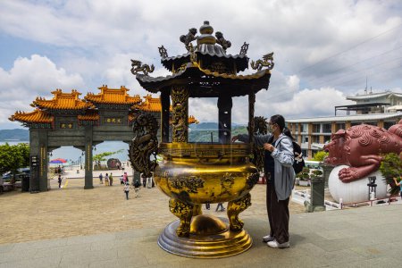 Foto de Sun Moon Lake, Taiwán - 23 de mayo de 2023: El encantador Templo de Wenwu, asombra con su gran arquitectura, colores vibrantes y aura sagrada. La mujer pone velas en el santuario para rezar - Imagen libre de derechos