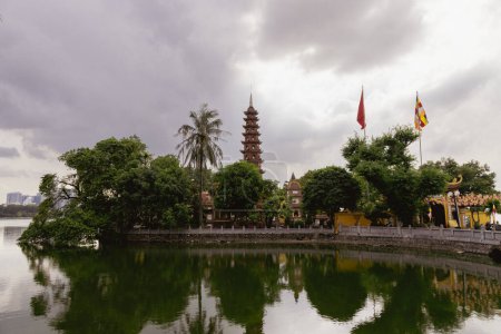 Foto de Hanoi, Vietnam - 28 de mayo de 2023: La pagoda Tran Quoc, situada en una pequeña isla en el lago oeste de Hanoi, es un antiguo templo budista conocido por su rica historia, su alta estupa esbelta y su hermoso jardín. - Imagen libre de derechos