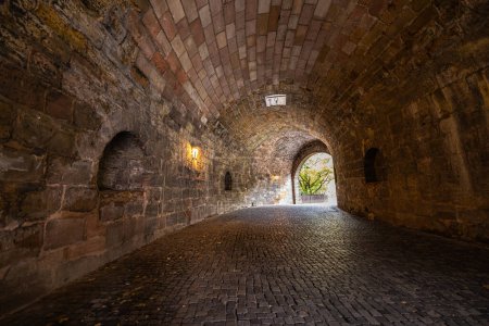 Foto de El túnel de entrada al Kaiserburg en Nuremberg, Alemania. Presenta un foso profundo y protector que rodea sus paredes, lo que aumenta su encanto medieval y su importancia histórica. Castillo imperial Nuremberg - Imagen libre de derechos
