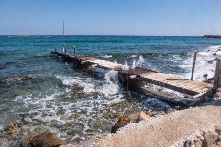 Téléchargez les photos : Admirez la beauté durable d'une jetée en bois altérée alors qu'elle rencontre les vagues incessantes de la Méditerranée en Crète, en Grèce. - en image libre de droit