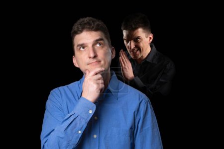 Photo for A friendly-looking young man to whom his evil inner voice is whispering something from the shadow behind - Royalty Free Image
