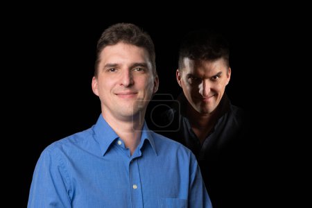 Photo for Nice looking young man with an evil character, a wicked looking face standing in the shadows behind him - Royalty Free Image