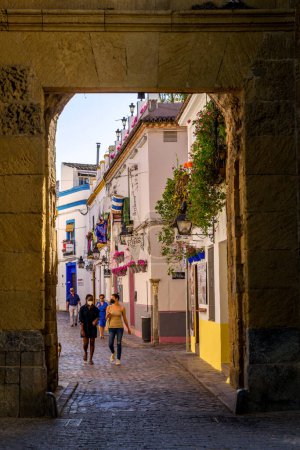 Photo for Cordoba, Spain - May 26. 2022: The ancient gate and colorful houses inside the old ticy in the morning light, Cordoba, Spain - Royalty Free Image