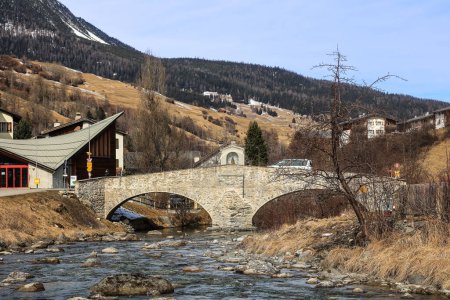 Téléchargez les photos : Le pont en pierre à double arche sur la rivière Julia dans le village alpin suisse Savognin avec sanctuaire de Sainte-Marie. Il a été construit en 1682. - en image libre de droit