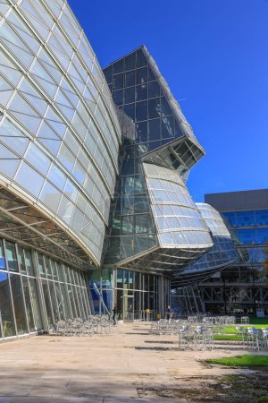 Foto de Basilea, Suiza - 25 de octubre de 2022: La estructura de vidrio y acero del edificio Novartis Pharma AG diseñada por Frank O. Gehry - un edificio futurista para cafeterías, restaurantes y foros. - Imagen libre de derechos