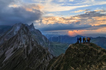 Foto de Senderistas de pie en la cima de la colina esperando el atardecer en la cumbre de montaña más espectacular de Alpenstein, Suiza - Imagen libre de derechos