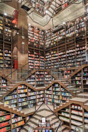 Foto de Chongqing, China - 20 de octubre. 2023: El diseño interior único de la librería Zhongshuge en Chongqing, utilizando escaleras cortas y espejo en el techo para presentar formas geométricas mágicas. - Imagen libre de derechos