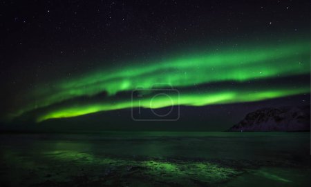 Aurora boreal o luz polar o luz septentrional sobre la playa de Skagsanden con reflejo en la orilla
