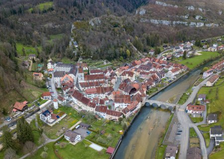 Téléchargez les photos : Vue aérienne de la petite ville médiévale St-Ursanne sur la rivière Doubs sous les montagnes du Jura. Saint-Ursanne a déjà été récompensée comme l'une des plus belles villes de Suisse. - en image libre de droit