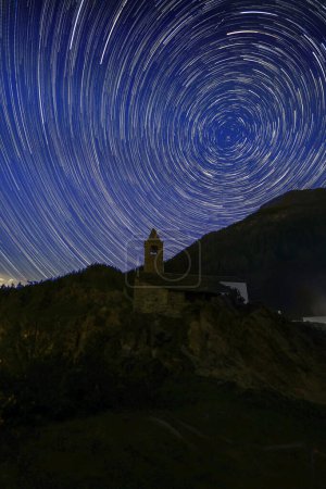 Star Trail over the chapel of San Romerio on cliff, Grisons, Switzerland