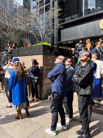 Foto de NUEVA YORK-ABRIL 8 - Los neoyorquinos ven el eclipse solar el 8 de abril de 2024 en el centro de Manhattan. - Imagen libre de derechos