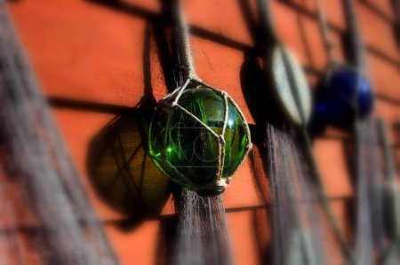 Foto de Old fashioned fishing net with colorful glass balls and bobbers hanging on a red wall - Imagen libre de derechos
