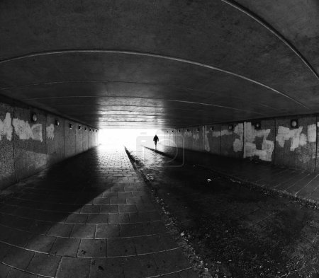 Photo for Young man walking through a run down urban tunnel - Royalty Free Image