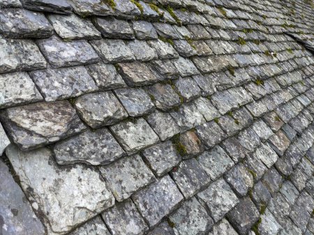 Old broken stone roof tiles, slate grey with moss and broken tiles