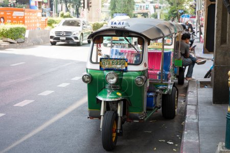 Foto de Bangkok, Thailand- 13 Feb, 2023: Traditional tuk-tuk on the road in Bangkok. Tuk tuks are motorized 3-wheeled rickshaws that ferry passengers around - Imagen libre de derechos