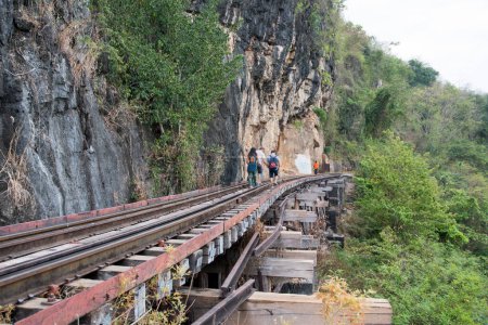 Téléchargez les photos : Kanchanaburi, Thaïlande 16 Feb, 2023 : Les touristes marchent le long du pont ferroviaire Tham Krasae, Kanchanaburi. Il a été construit pendant la Seconde Guerre mondiale de seulement 17 jours au printemps 1943. - en image libre de droit