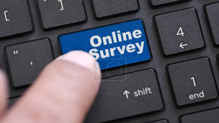 Online survey word on blue enter keypad on black laptop