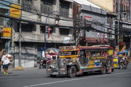 Foto de Manila, Filipinas-15 Oct 2023: Jeepney taxi conduce por la carretera en el centro de Manila. Jeepneys son vehículos de utilidad pública similares a minibuses - Imagen libre de derechos