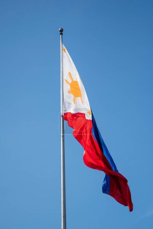 Philippines flag waving in the wind against a blue sky.
