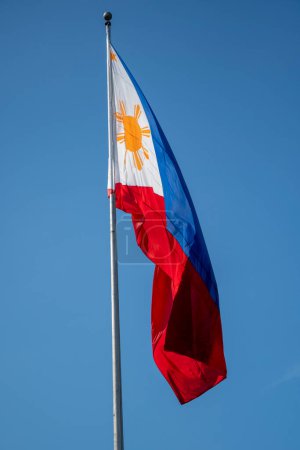 Philippinen-Flagge weht im Wind vor blauem Himmel.
