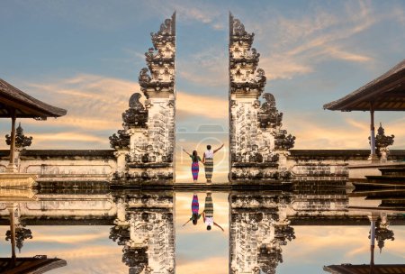 Glückliches asiatisches Paar, das vor den Toren des Himmelstempels steht und sich an der Hand hält. Perfekte Flitterwochen-Idee. Lempuyang Luhur Tempel auf Bali, Indonesien.