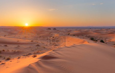 Sunset over the sand dunes in the desert. Arid landscape of the Sahara desert