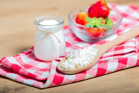 Grains de kéfir dans une cuillère en bois devant des tasses de yogourt au kéfir Parfaits. Kefir est l'un des meilleurs aliments de santé disponibles fournissant des probiotiques puissants.