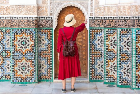Photo for Girl dressing in red with hat looking the Ben Youssef Madrasa in marrakesh, morocco - Royalty Free Image