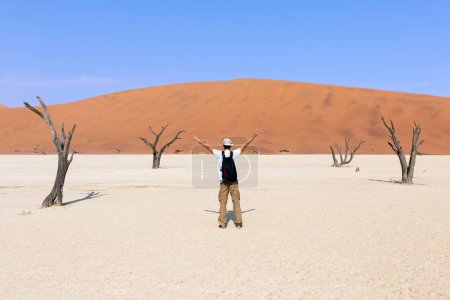 Photo for A young tourist with open arms at Deadvlei, Sossusvlei. Namibia, Africa - Royalty Free Image