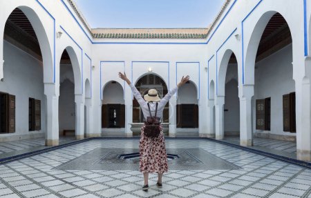 Young woman with red dress and hat visiting typical Moroccan architecture in Marrakesh. Morocco - Travel and vacation lifestyle concept