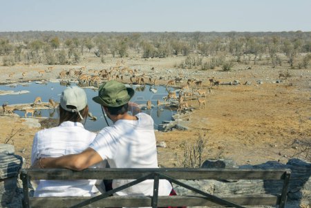 Rückansicht eines jungen Paares, das Tiere in der afrikanischen Savanne beobachtet - Reisekonzept