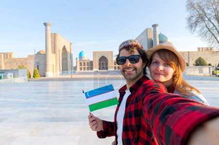 feliz pareja de turistas tomando una selfie con Registan como fondo en la ciudad de Samarkand, Uzbekistan, Asia Central