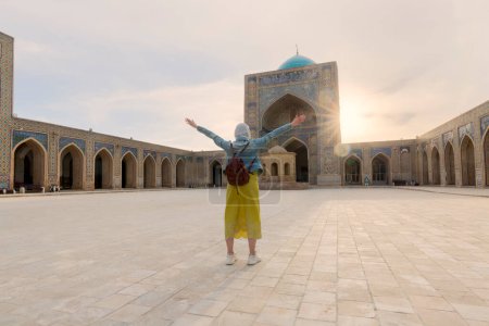 Joven turista con las armas dentro de la Mezquita Kalyan, parte del complejo Po-i-Kalyan en Bujará, Uzbekistán