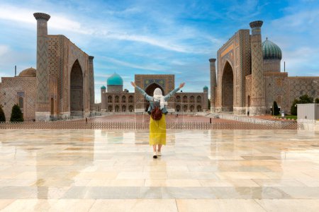 Usbekistan, Samarkanda - junges Mädchen steht mit offenen Armen und blickt auf den Registan-Platz