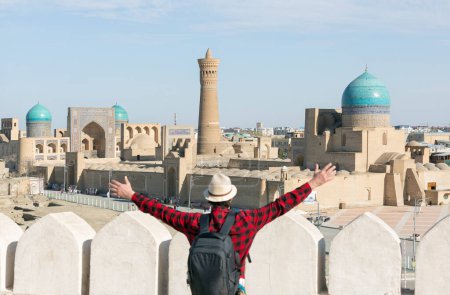 happy tourist with arms up looking at bukhara city - travel concept