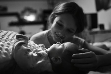 Photo for Close up of young mother looking at newborn daughter in bedroom, black and white - Royalty Free Image