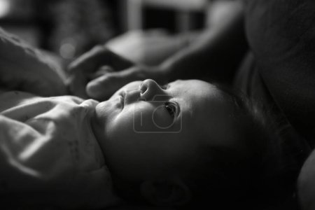Photo for Baby lies in bed with open eyes. Baby woke up. Black and white - Royalty Free Image
