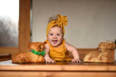 Téléchargez les photos : Des bonbons sur la table de Pâques. Une petite belle fille joue avec un agneau sur la table. Agneau de Pâques - en image libre de droit