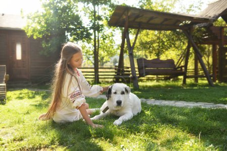 Téléchargez les photos : Preteen fille portant des vêtements traditionnels ukrainiens avec son chien dans le parc d'été - en image libre de droit