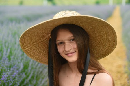 Téléchargez les photos : Portrait d'une femme en chapeau. Belle fille aux cheveux longs souriant. fille dans le champ de lavande - en image libre de droit