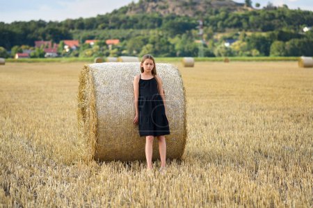 Foto de Chica joven cerca de pajar en un campo cosechado - Imagen libre de derechos
