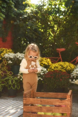 Téléchargez les photos : Fille avec des fleurs dans le jardin. petite fille avec un bouquet de fleurs - en image libre de droit