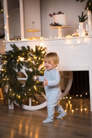 Photo for Little baby decorating christmas tree at home - Royalty Free Image