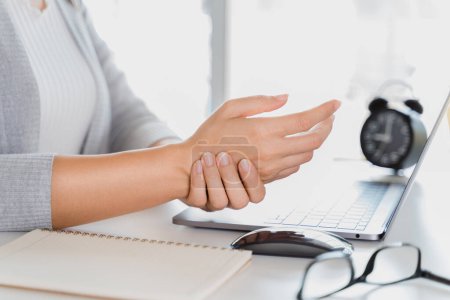 Foto de Mujer de primer plano sosteniendo su dolor de mano de usar el ordenador portátil mucho tiempo. Concepto de síndrome de oficina. - Imagen libre de derechos